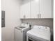 This laundry room is equipped with white cabinets, modern washer and dryer, and electrical panel at 417 E College Ave # 302, Decatur, GA 30030