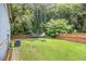 Large, grassy fenced backyard includes a fire pit, a shed, and a trampoline at 4835 Kellys Mill Nw Dr, Lilburn, GA 30047