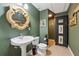 Rustic bathroom featuring pedestal sink, decorative mirror, and wooden cabinet with fish themed decor at 1042 Bailey Rd, Woodstock, GA 30188