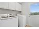 Bright laundry room features a washer, dryer, and storage cabinets near the back door at 1400 Land Rd, Canton, GA 30114
