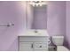 Bathroom with white vanity, toilet, mirror, and light fixture contrasted against the light purple walls at 3348 Summit Turf Ln, Snellville, GA 30078