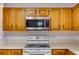 Oak kitchen cabinets paired with white countertops, a white electric range, and a stainless steel microwave at 3348 Summit Turf Ln, Snellville, GA 30078