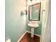 Charming powder room with a pedestal sink, decorative mirror, and stylish wood look flooring at 3534 Clancy Way, Smyrna, GA 30080