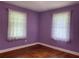Cozy bedroom with purple walls, bright windows with sheer curtains, and hardwood floors at 410 S Gordon Sw Rd, Mableton, GA 30126