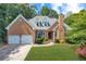 Charming brick home featuring a two-car garage, well-manicured lawn, and classic architectural details at 10880 Windham Way, Alpharetta, GA 30022