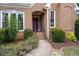 Inviting entrance with a brick walkway, garden, and arched porch leading to a solid front door at 10880 Windham Way, Alpharetta, GA 30022
