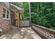 Side view of a wooden back porch surrounded by brick walls, greenery, and mature trees at 2973 Payton Ne Rd, Atlanta, GA 30345