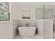 Bright bathroom featuring a soaking tub, stone tile, and a separate glass enclosed shower at 2973 Payton Ne Rd, Atlanta, GA 30345