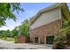 Side view of an attached brick garage with two wooden doors, surrounded by greenery and a driveway at 2973 Payton Ne Rd, Atlanta, GA 30345