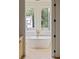 Bright bathroom featuring soaking tub, modern fixtures, and beautiful backyard views at 11560 Serenbe Ln, Chattahoochee Hills, GA 30268