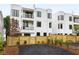 Modern townhome exterior with black framed windows, balconies, and a wooden privacy fence at 11560 Serenbe Ln, Chattahoochee Hills, GA 30268