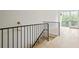 Hallway with modern black railing, leading to a naturally lit doorway and hardwood floors at 11560 Serenbe Ln, Chattahoochee Hills, GA 30268