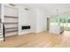 Open-concept living space featuring hardwood floors, marble fireplace, built-in shelves, and adjacent kitchen at 11560 Serenbe Ln, Chattahoochee Hills, GA 30268