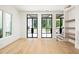 Sunlit living room boasting hardwood floors, black-framed windows, and custom shelves at 11560 Serenbe Ln, Chattahoochee Hills, GA 30268