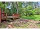 A backyard deck featuring wood planks and stairs surrounded by beautiful greenery and a brick walkway at 4246 Rue Saint Michel, Stone Mountain, GA 30083