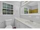Bright bathroom features a white vanity with sink, toilet, mirror, and tiled wall at 4246 Rue Saint Michel, Stone Mountain, GA 30083
