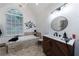 Bright bathroom with a tub, chandelier, modern vanity, and a large window overlooking a garden at 525 Avala Ct, Johns Creek, GA 30022