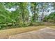 View of the backyard featuring a stone patio and a glimpse of the house through the trees at 5705 Cannonero Dr Dr, Alpharetta, GA 30005