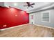 Bright bonus room features a red accent wall, ceiling fan, and door to backyard with updated laminate floors at 1235 Renaissance Se Ct, Mableton, GA 30126