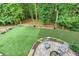 Aerial view of a lush backyard with a stone patio, fire pit, and putting green at 5930 Shannon Drive Dr, Cumming, GA 30040