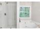 Bright bathroom showcasing a walk-in shower with subway tiles and a soaking tub under a window at 5930 Shannon Drive Dr, Cumming, GA 30040