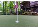 Manicured backyard putting green with lush artificial turf, framed by trees, a two-story deck, and rock landscaping at 5930 Shannon Drive Dr, Cumming, GA 30040