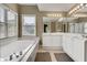 Bright bathroom featuring a white bathtub under a window and a mirrored vanity with white cabinets at 1685 Frazier Park Dr, Decatur, GA 30033