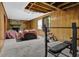 View of a basement with wood paneling, carpeting, weightlifting equipment, and a stone fireplace at 504 Rock Meadow Dr, Stone Mountain, GA 30088