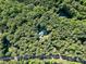 Breathtaking aerial view of a home nestled in a dense forest with a vibrant green metal roof at 5357 Highway 81, Loganville, GA 30052