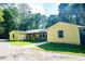 Charming yellow home exterior with a green roof, surrounded by mature trees at 5357 Highway 81, Loganville, GA 30052