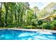 Private in-ground pool with a fenced area, surrounded by trees, and lush landscaping at 5357 Highway 81, Loganville, GA 30052