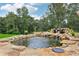 Backyard featuring a rock-lined pond and waterfall feature, surrounded by lush greenery at 3735 Hamilton Mill Rd, Buford, GA 30519