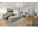 Staged main bedroom with tray ceilings, modern chandelier, hardwood floors, and access to other rooms at 3735 Hamilton Mill Rd, Buford, GA 30519