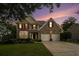 Charming brick home with manicured lawn, two-car garage, and lovely sunset in the background at 5925 Crescent Landing Dr, Cumming, GA 30028
