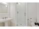 Modern bathroom featuring a glass shower door, hexagon tiles, and a pedestal sink with elegant fixtures at 968 Dean Nw Dr, Atlanta, GA 30318