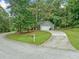 Home with an attached garage sits nestled on a corner lot with mature trees and a long driveway at 3235 Harms Way, Snellville, GA 30039