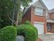 Exterior side view of a brick townhome featuring manicured bushes and an attached garage at 2131 Meadow Peak Rd, Duluth, GA 30097