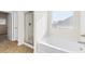 Bright bathroom featuring a large tub with shower, and window with blinds at 1494 Weeping Tree Cir, Auburn, GA 30548