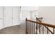 Hallway with carpet and wooden railings with a view into the next room with multiple windows at 1494 Weeping Tree Cir, Auburn, GA 30548