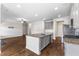 Shows the layout of the kitchen with an island, stainless steel appliances, and hardwood floors, and a peek of the fireplace at 1494 Weeping Tree Cir, Auburn, GA 30548