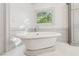 Bathroom with a free-standing soaking tub and a decorative leaded glass window at 4935 Stablegate Ct, Cumming, GA 30028