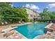A large in-ground swimming pool with diving board and a backyard view of a brick home at 4935 Stablegate Ct, Cumming, GA 30028