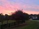 Scenic sunset view from property showcasing lush green lawn and a black rail fence at 4935 Stablegate Ct, Cumming, GA 30028