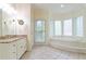 Spa-like bathroom featuring a jacuzzi tub surrounded by large windows and a granite topped vanity at 920 Waters Reach Ct, Alpharetta, GA 30022