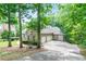 View of brick home showcasing an attached two-car garage surrounded by lush greenery and mature trees at 920 Waters Reach Ct, Alpharetta, GA 30022