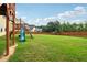 Lush backyard with vibrant green grass, mature trees, a playset and a secure wooden fence at 1564 Brunswick St, Lithia Springs, GA 30122