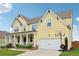 Two-story yellow home with a covered porch, lush landscaping, and an attached two-car garage at 1564 Brunswick St, Lithia Springs, GA 30122