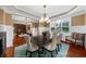 Elegant dining room featuring wainscoting, chandelier, seating for six, and view to living room at 4425 Martel Dr, Cumming, GA 30040