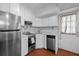 Kitchenette with stainless steel appliances, white cabinets, updated countertops, and wood-look tile flooring at 3016 Ansley Manor Ct, Snellville, GA 30078
