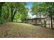 A view of the property, featuring a spacious lawn bordered by mature trees for privacy and shade at 6658 Collins Ct, Riverdale, GA 30274